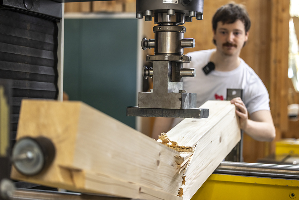 Ein Mann arbeitet. Ein Stück Holz bricht.