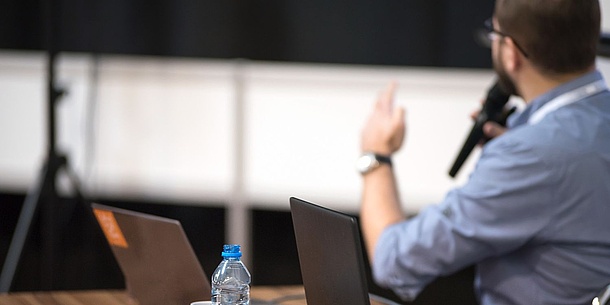 A man with a microphone in a lecture hall.