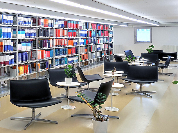 Loungebereich der Hauptbibliothek mit Sitzgelegenheiten und Pflanzen zwischen den Bücherregalen