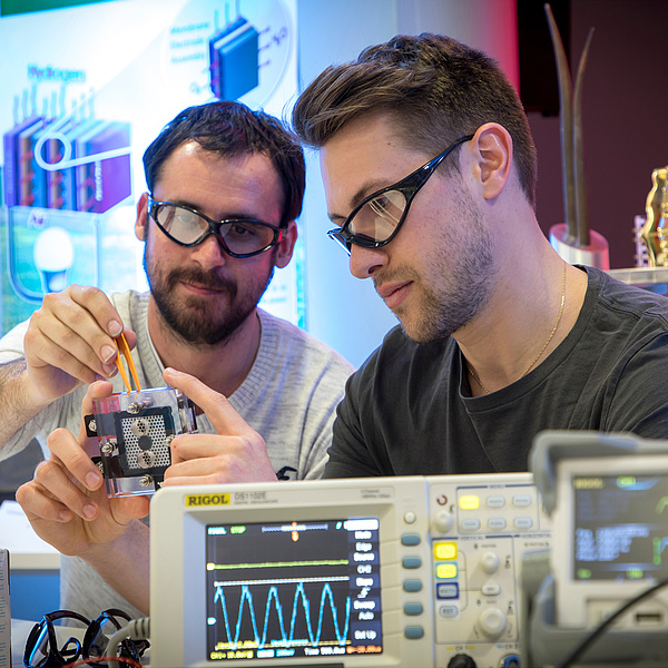 Two young men wearing protective glasses in an electronics laboratory.