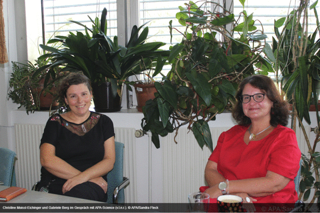 Christine Moiss-Eichinger und Gabriele Berg sitzen nebeneinander im Büro, im Hintergrund viele Pflanzen
