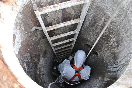 A man in a protective suit in a concrete shaft.