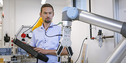 A man is standing behind an industrial robot.