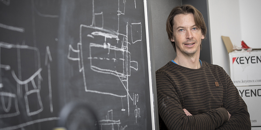 A man leans against a blackboard.