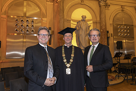 Three men stand next to each other and look into the camera