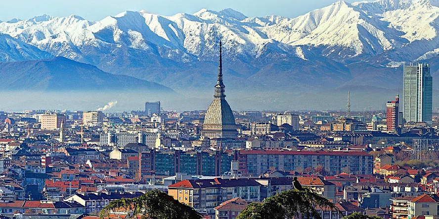 View over the roofs of a city with snow-capped mountains in the background.