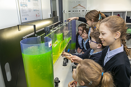 Several children look at a glass structure filled with liquid.
