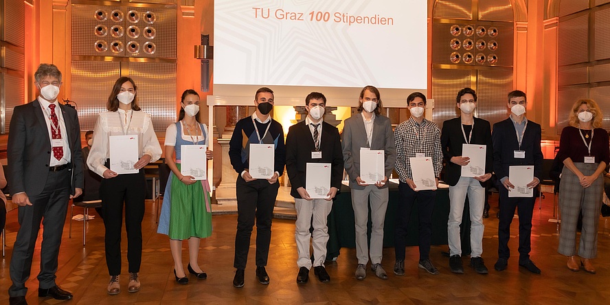 Gruppe von jungen Menschen mit Urkunden, flankiert von zwei Repräsentanten der TU Graz