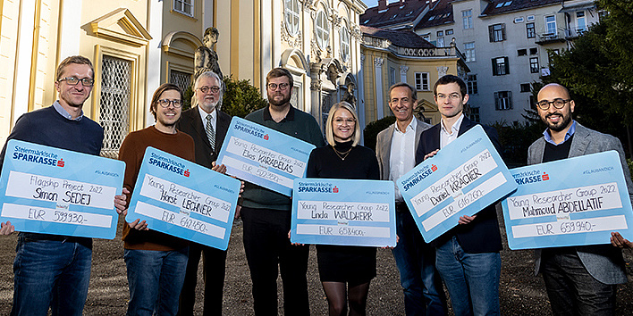 Mehrere Personen halten Schecks in der Hand.