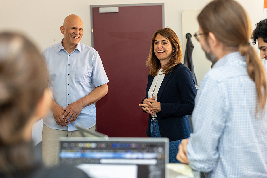 Bildquelle: Frankl – TU Graz Ein Mann und eine Frau stehen nebeneinander, einige weitere Menschen sind im Raum.