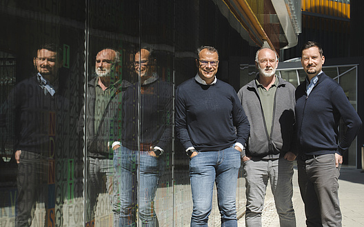 Three smiling men stand next to each other.