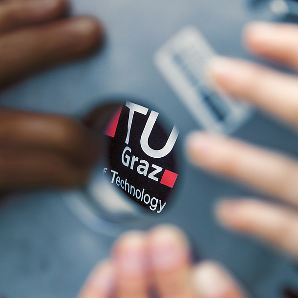 TU Graz logo and different hands. Source: Lunghammer – TU Graz