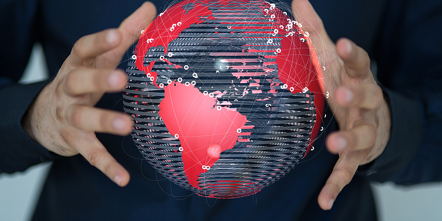 Two hands hold a stylised globe with the continents coloured in red.