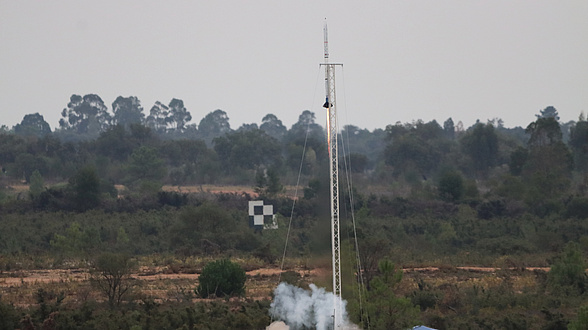 Eine Rakete startet von einer mit Büschen bewachsenen Ebene.