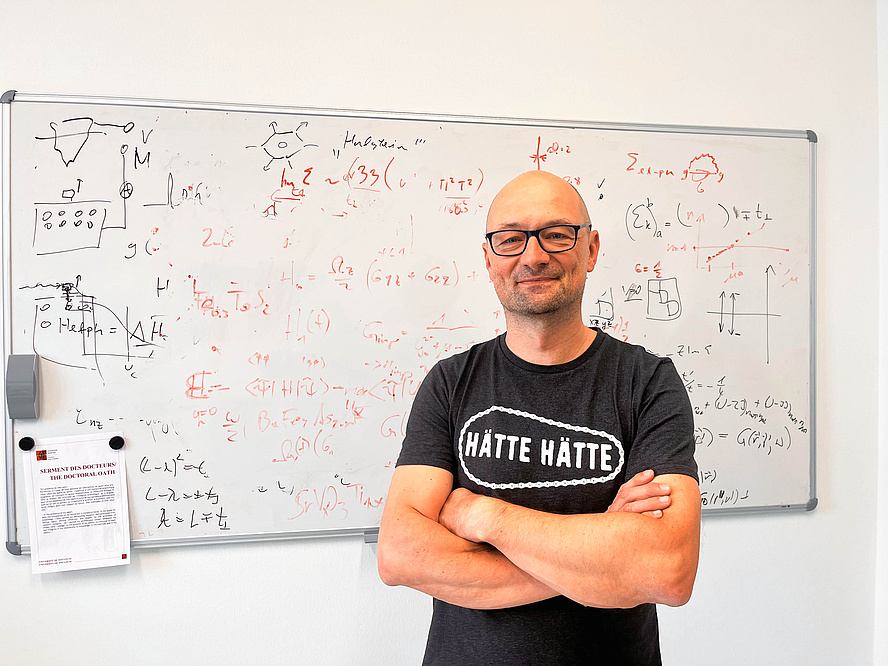 Ein Mann lehnt an einem vollgeschriebenen Whiteboard.