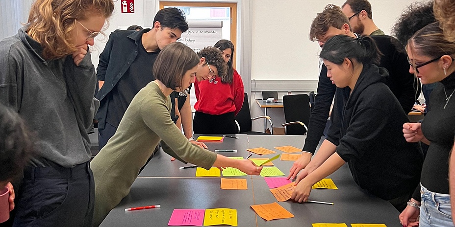Students are bent over a table with brightly colored cards. 