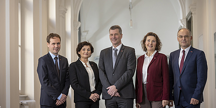 Two women and three men smiling in a row