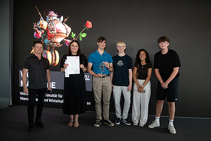 Six people stand together on a stage and smile into the camera.