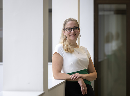 A woman leans against a balustrade and looks into the camera.