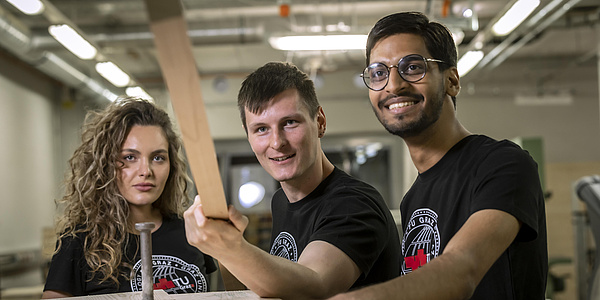 A young woman and two young men work together in a technical laboratory.
