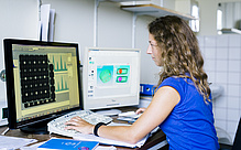 Woman in front of a computer screen with visualized data.