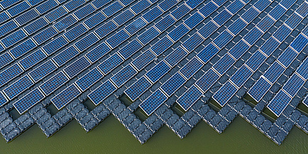 Eine große Fläche von Solarpaneelen auf einem See aus der Vogelperspektive.