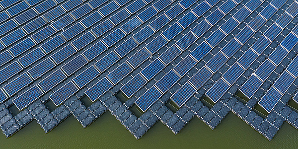 Eine große Fläche von Solarpaneelen auf einem See aus der Vogelperspektive.