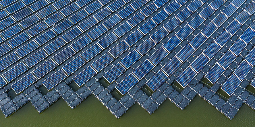A bird's eye view of a large area of solar panels on a lake.