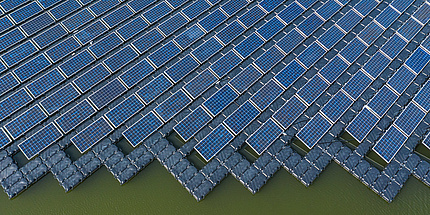 A bird's eye view of a large area of solar panels on a lake.