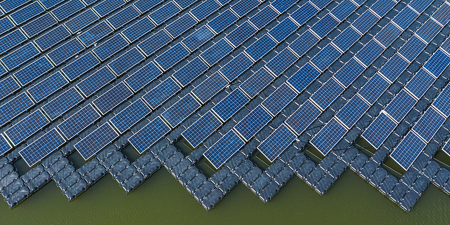 Eine große Fläche von Solarpaneelen auf einem See aus der Vogelperspektive.
