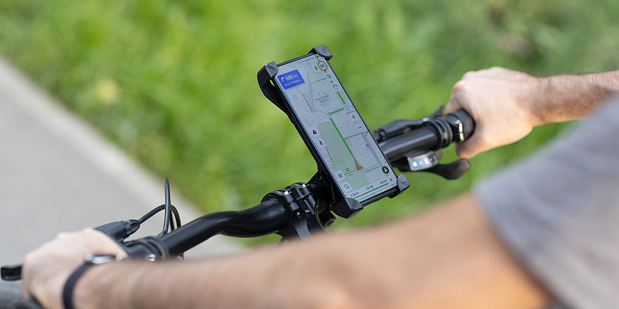 A bicycle handlebar with a smartphone attached to it, displaying a navigation app on the screen.