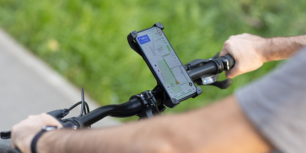A bicycle handlebar with a smartphone attached to it, displaying a navigation app on the screen.