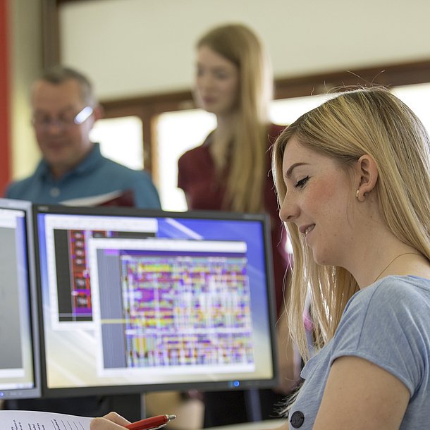 A student in front of two screens where you can see circuits.