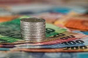 a stack of coins on colorful banknotes