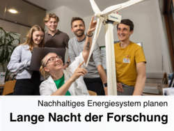 Eine Person zeigt auf ein Miniaturwindrad und 4 Leute stehen dahinter und schauen zu.