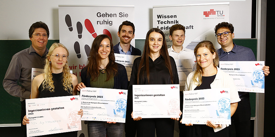Four women and four men look into the camera and hold a certificate, the award for dissertations and master theses at TU Graz with special social relevance, in their hands, beaming with joy.