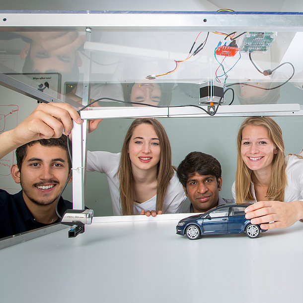 Four young people with a model car and a camera