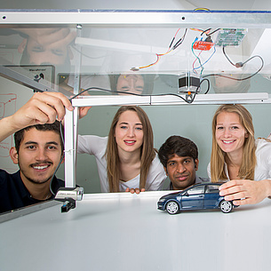 Vier junge Leute mit Modellauto und Kamera