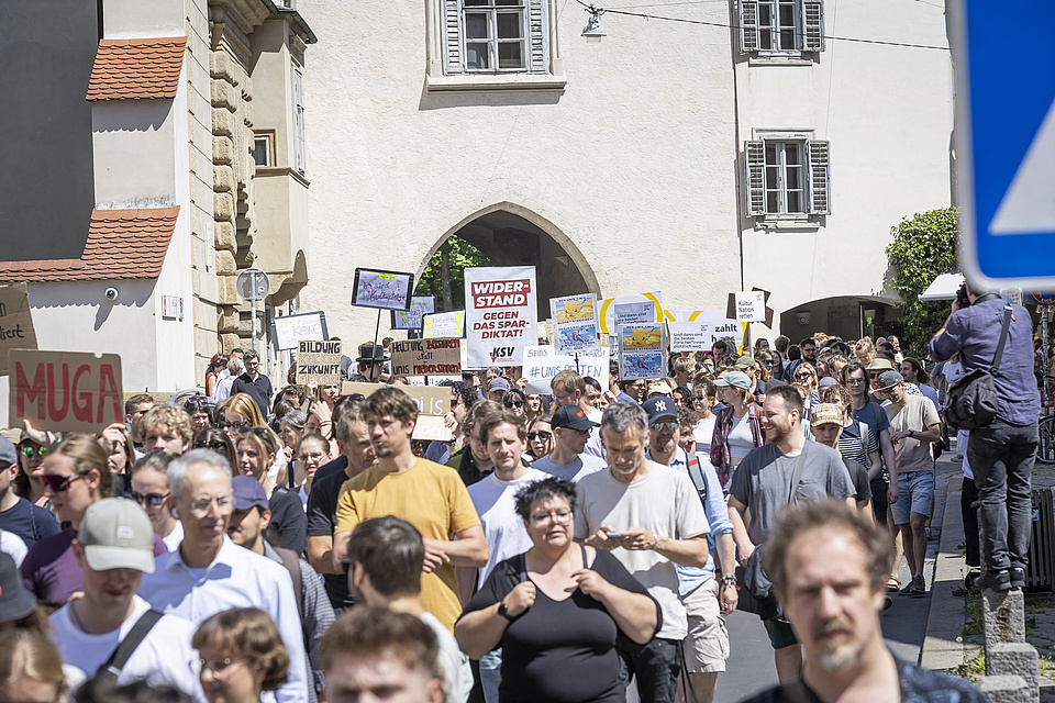 A large crowd is moving along a street towards the camera.