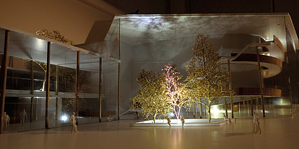 Architekturmodell eines Hauses, davor steht eine Baumgruppe - das Ensemble wir lichttechnisch bespielt