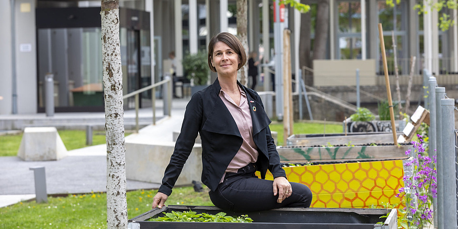 A woman is sitting on a raised bed.