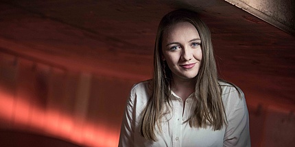 Young woman with white shirt in front of red illuminated background