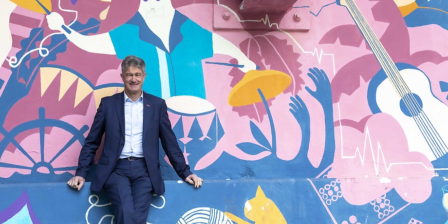Man in suit in front of brightly coloured wall