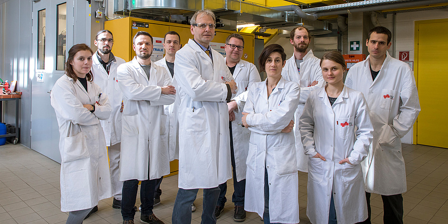 A few people dressed in white lab coats are standing in a laboratory.