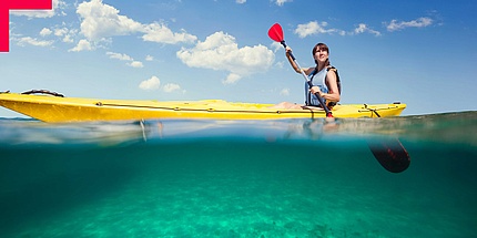 Young woman sitting in yellow canoe and paddling