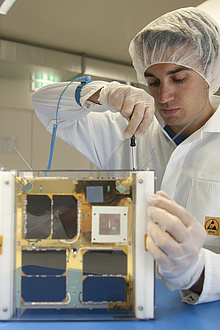 Wissenschaftliche Mitarbeiter/in beim Bau von TUGSAT-1 im Reinraum an der TU Graz.