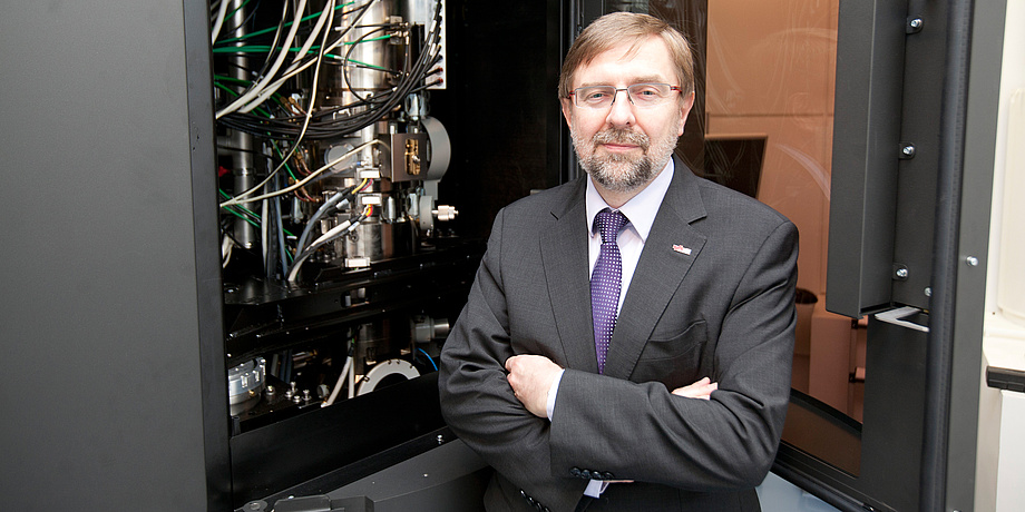 Institutsleiter Ferdinand Hofer steht mit verschränkten Händen vor dem geöffneten Elektronenmikroskop