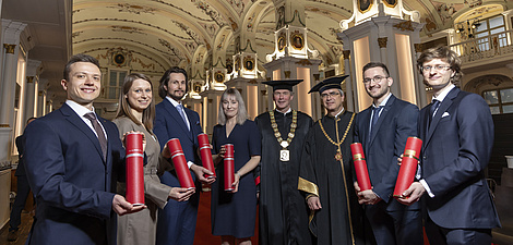 Eight people smile at the camera. They are festively dressed.