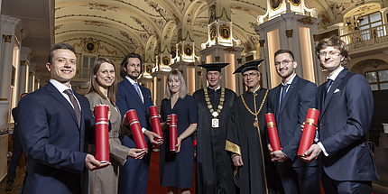 Eight people smile at the camera. They are festively dressed.
