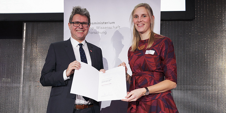Ein Mann und eine Frau halten eine Urkunde in der Hand.